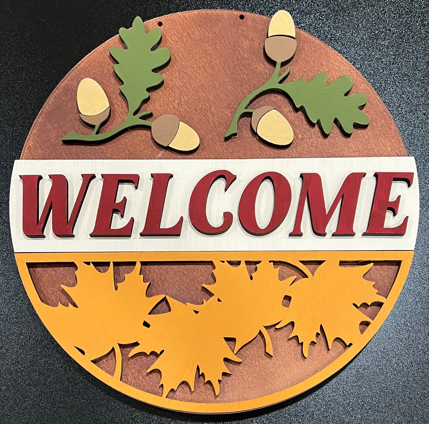 Unpainted wooden "WELCOME" sign with fall leaves and acorns.
