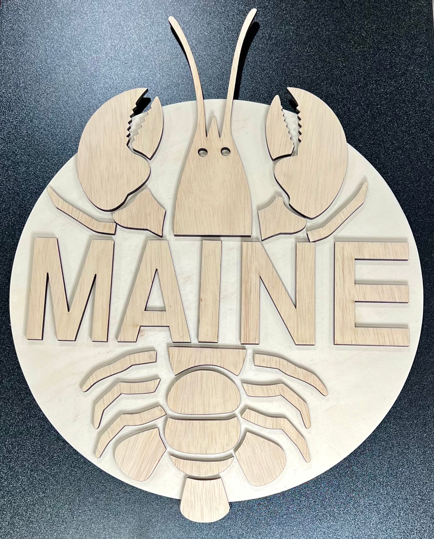 Unpainted wooden sign featuring a lobster design with the word "MAINE" in the center.