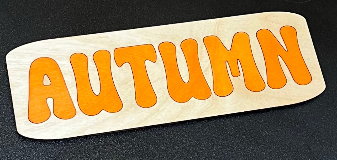 Wooden puzzle with the word "AUTUMN" in orange letters.