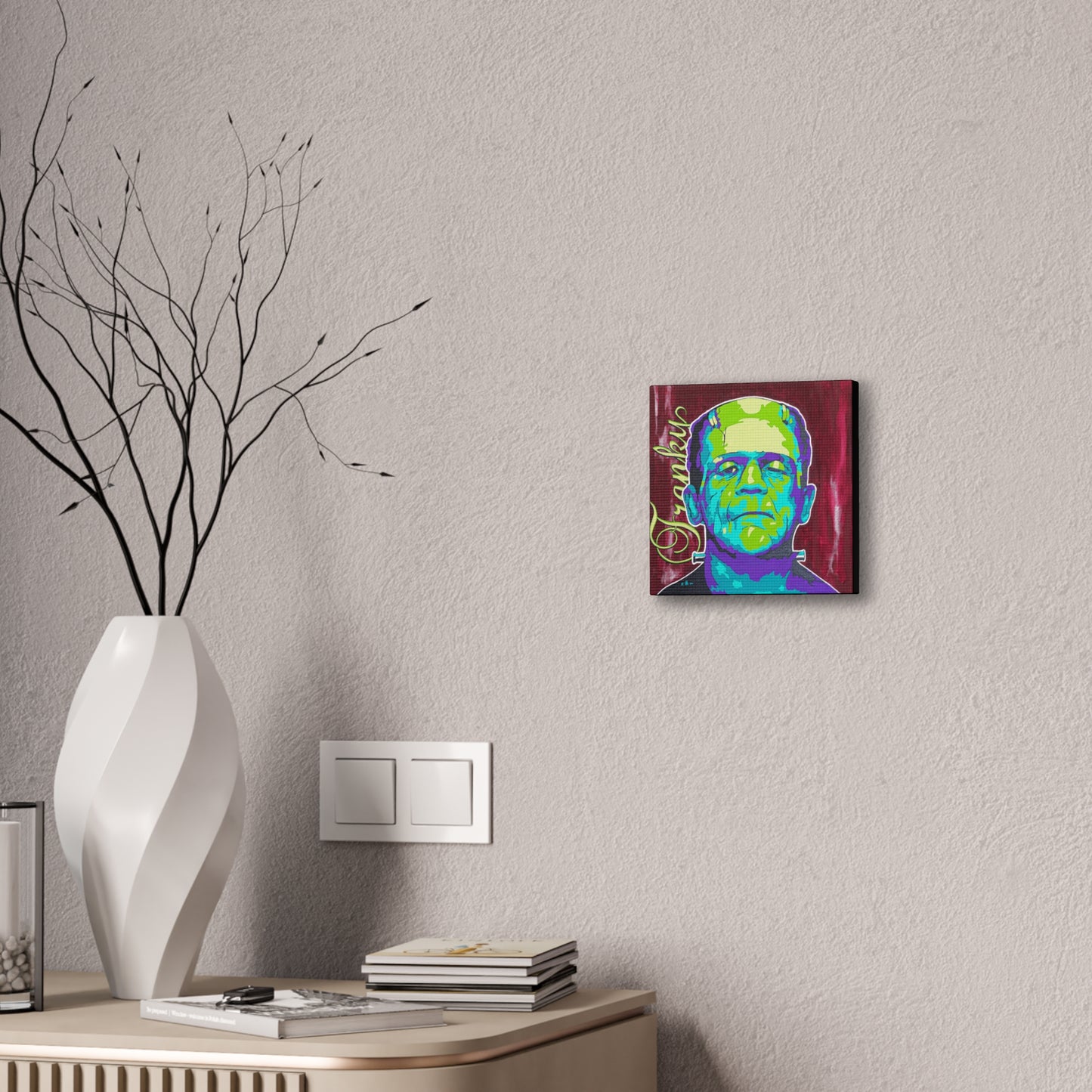 A colorful canvas print of Frankenstein's monster hangs on a textured wall.
