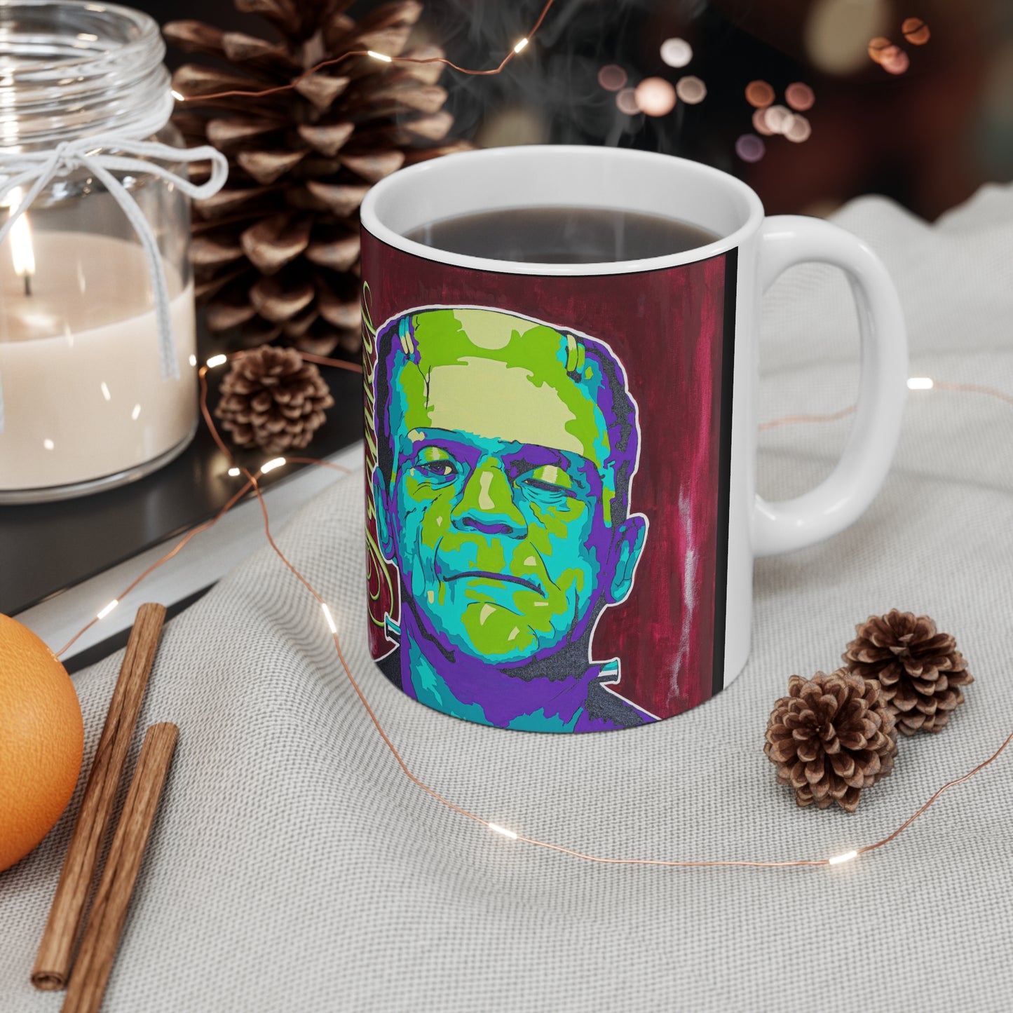 A white ceramic mug with a colorful Frankenstein's monster design sits on a table.