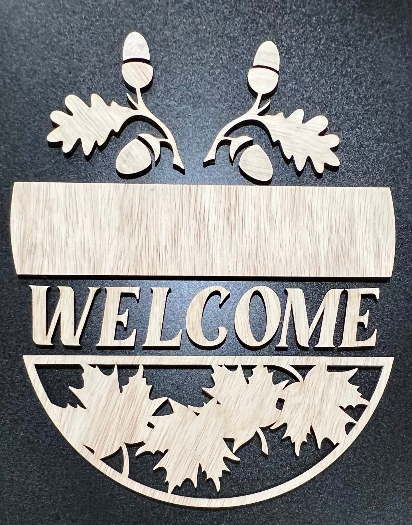 Unpainted wooden "WELCOME" sign with fall-themed leaf and acorn cutouts.