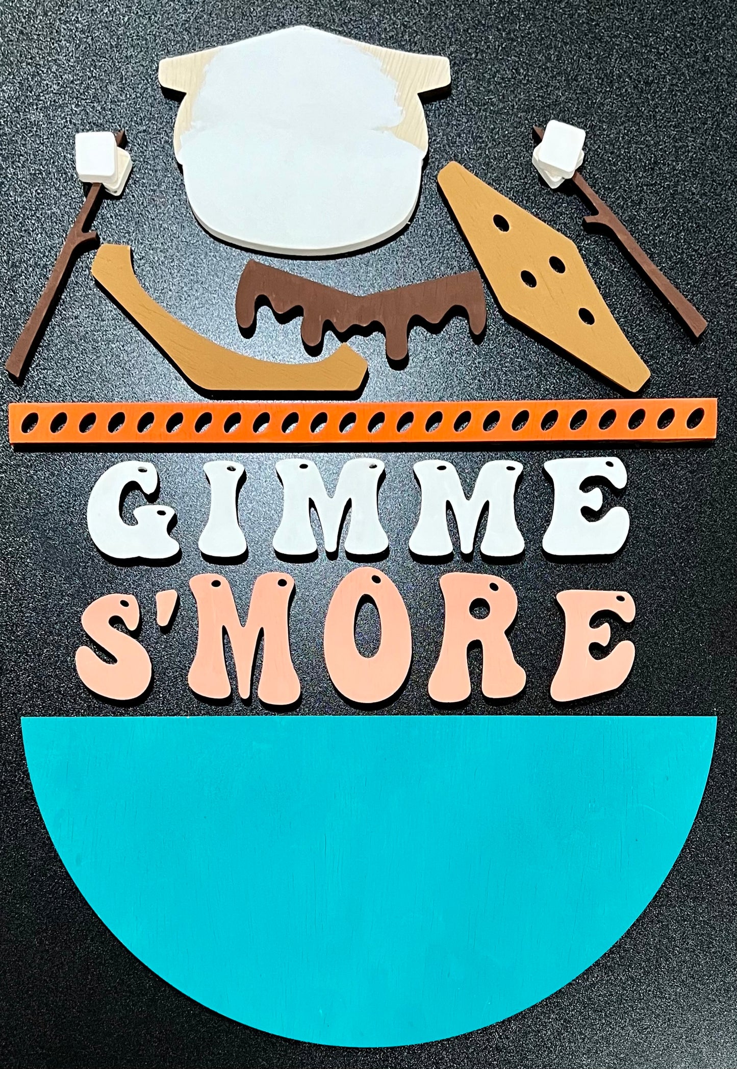 Unpainted wood "Gimme S'more" sign kit with marshmallow, chocolate, and graham cracker pieces.