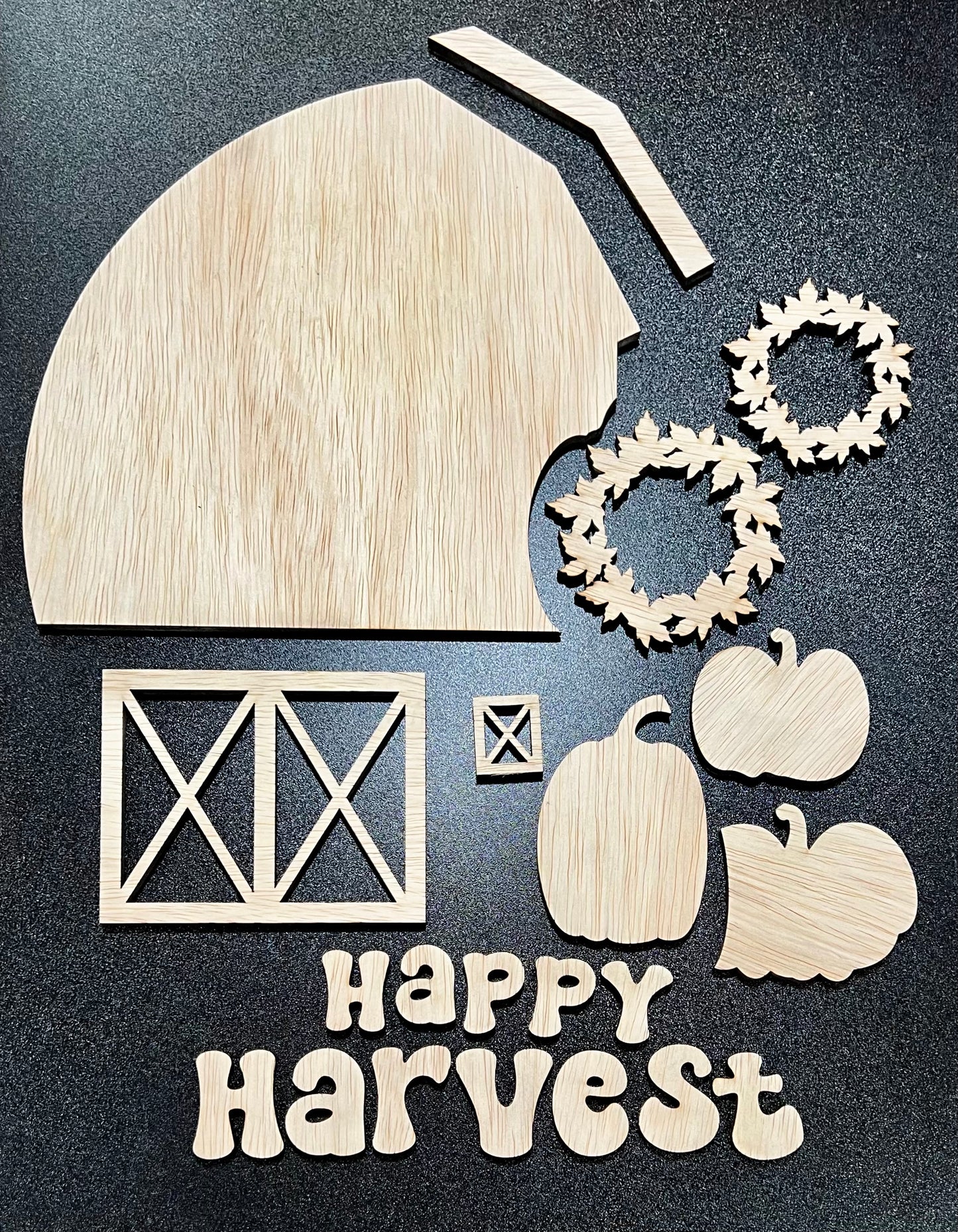 Unpainted wooden "Happy Harvest" sign kit with barn, wreaths, pumpkins, and window pieces.