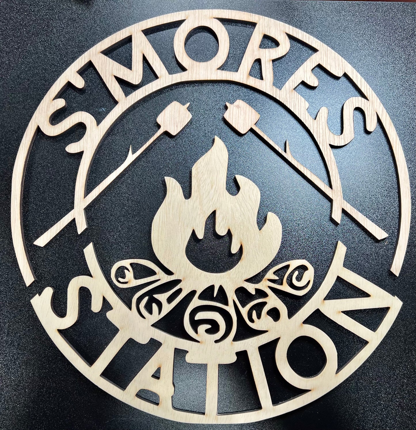 Unpainted wooden "S'mores Station" sign with a campfire and marshmallows on sticks.