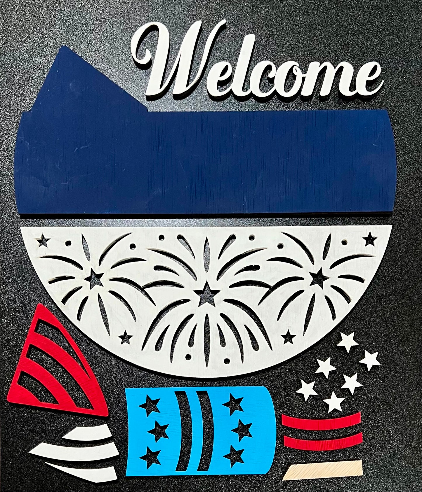 Unpainted wooden sign kit with "Welcome" text and firework-themed pieces.