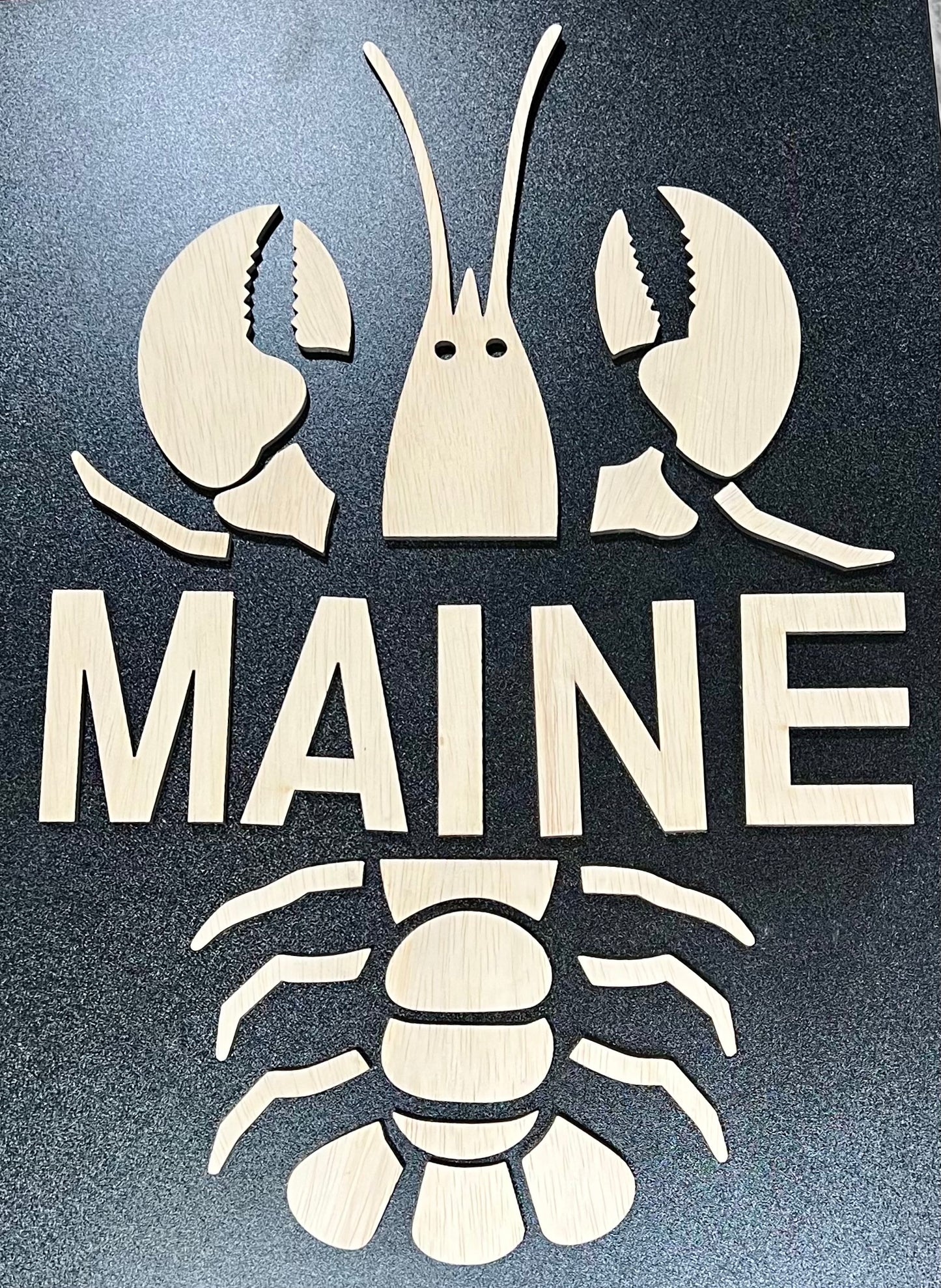 Unpainted wooden sign featuring a lobster and the word "MAINE" on a dark background.
