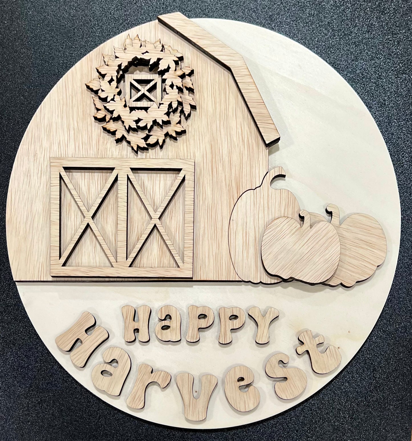 Unpainted wooden "Happy Harvest" sign with a barn, wreath, and pumpkins.