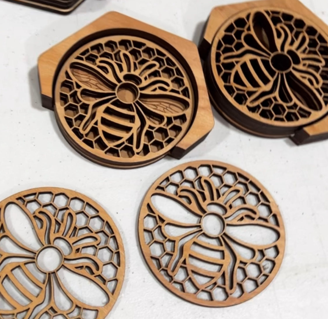 Four laser-cut wooden bee coasters with a matching hexagonal holder.