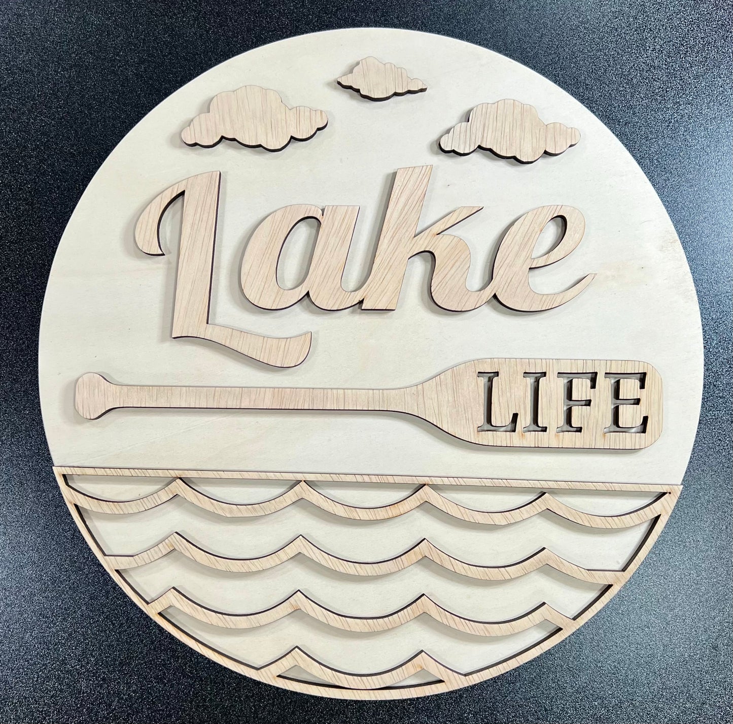 A round wooden sign features the words "Lake Life" with clouds, a paddle, and waves.