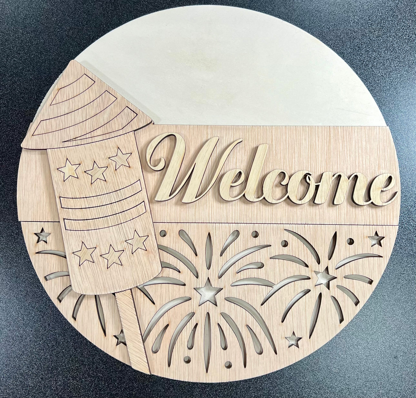 Unpainted wooden "Welcome" sign with a firework and rocket design.