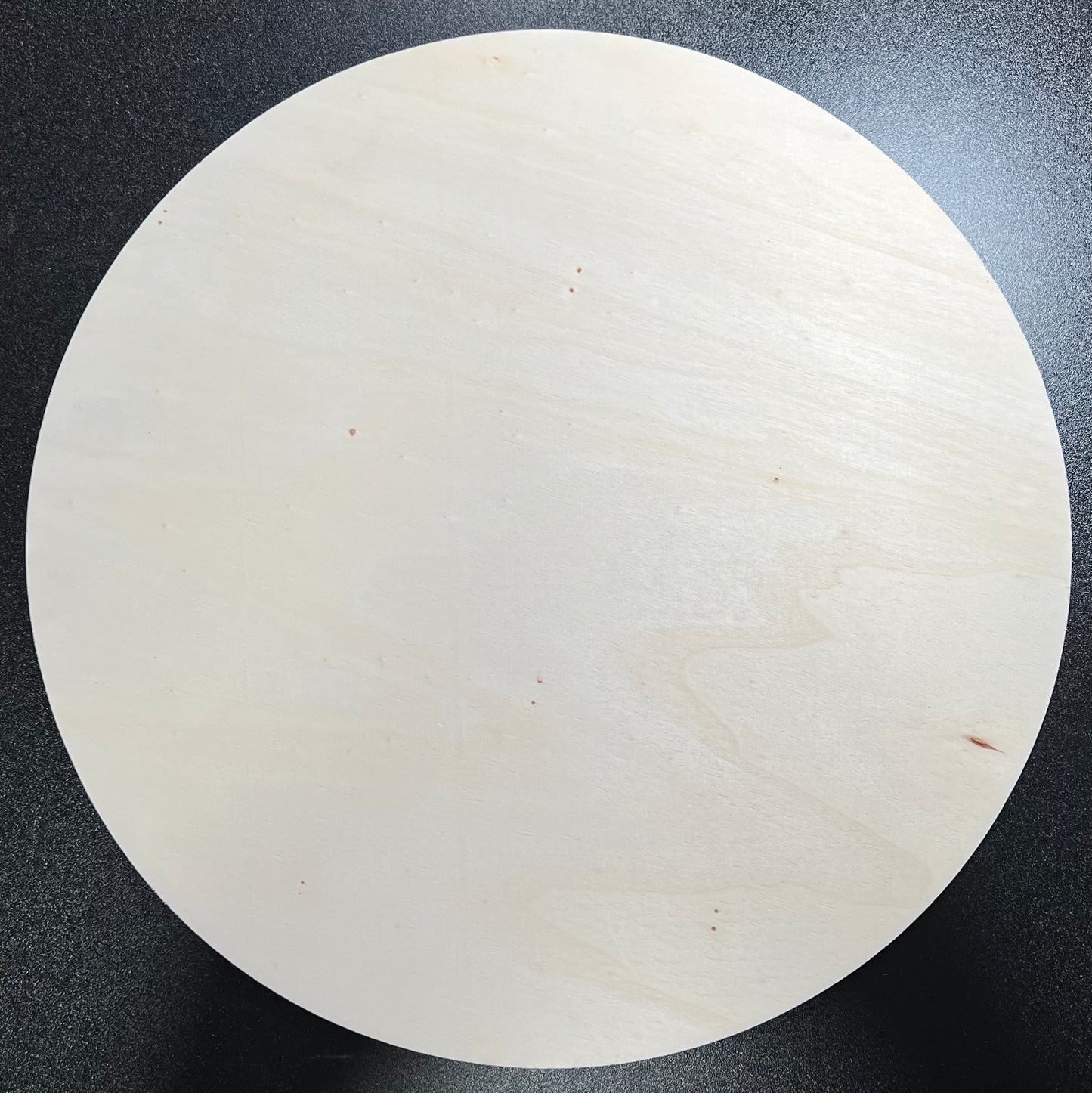 A round, unpainted wooden sign with a smooth, light-colored surface.
