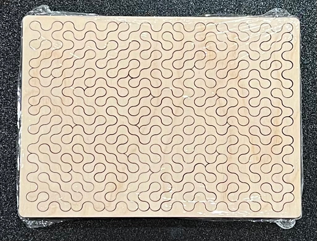 A wooden puzzle with many interlocking, wavy pieces is sealed in plastic.