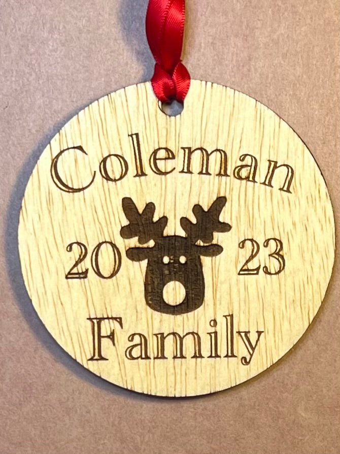 A round wooden ornament engraved with "Coleman 2023 Family" and a reindeer.