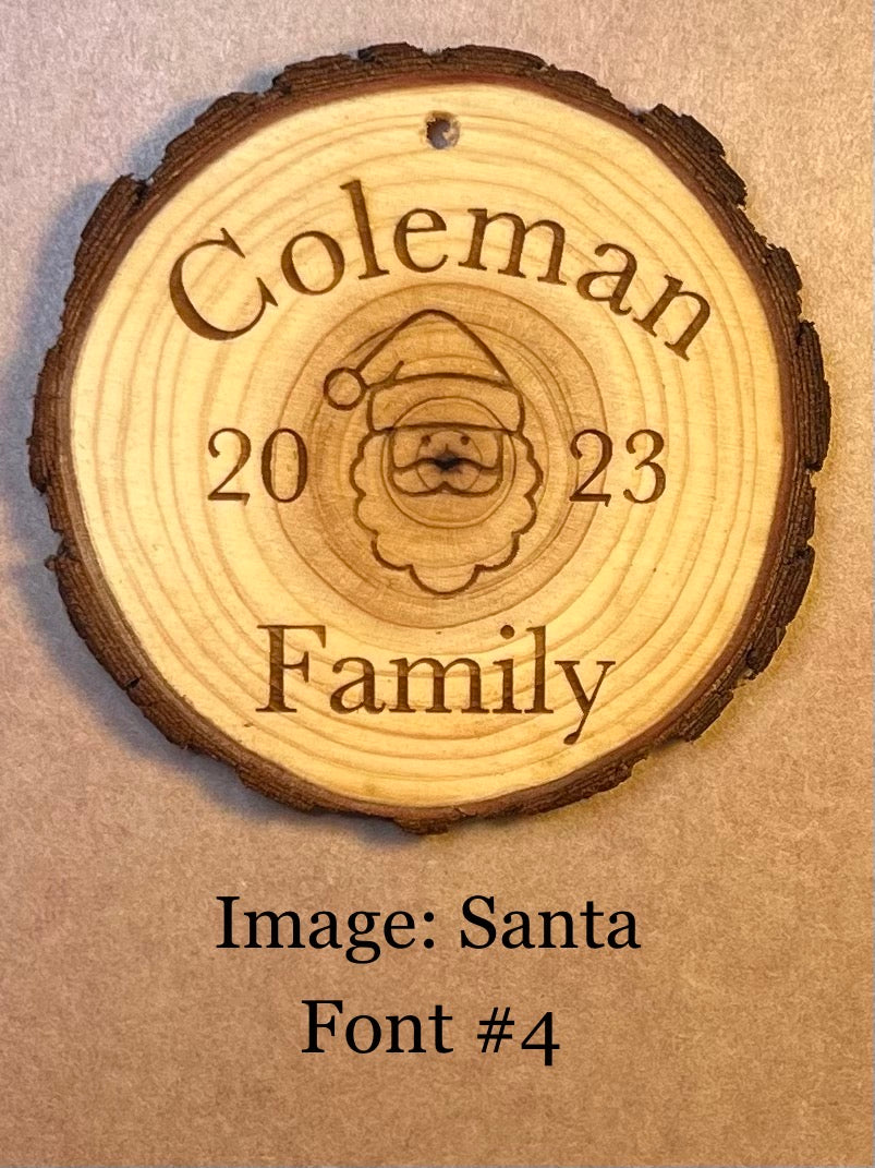 A personalized log wood round ornament is engraved with "Coleman 2023 Family" and a Santa image.