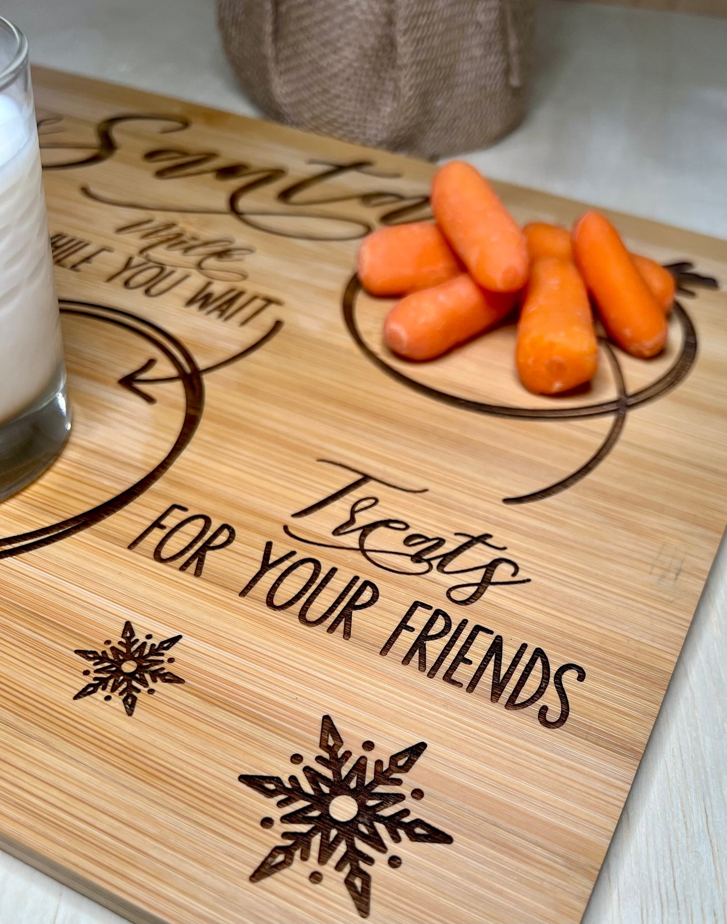 Engraved bamboo tray with a glass of milk and baby carrots.