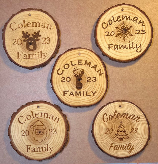 Five personalized wood slice ornaments, each engraved with "Coleman 2023 Family" and a holiday design.
