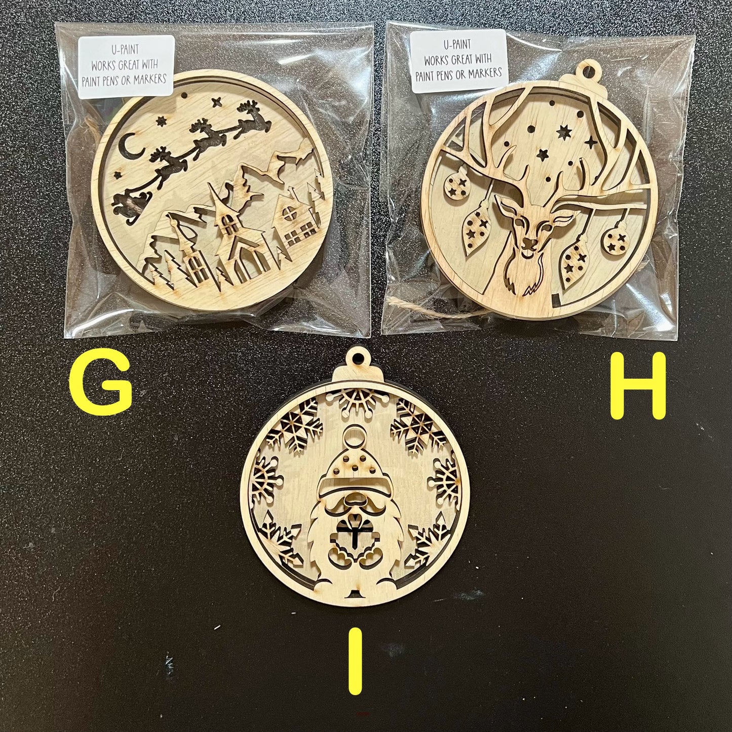 Three unfinished, layered wooden Christmas ornaments are displayed on a dark surface.