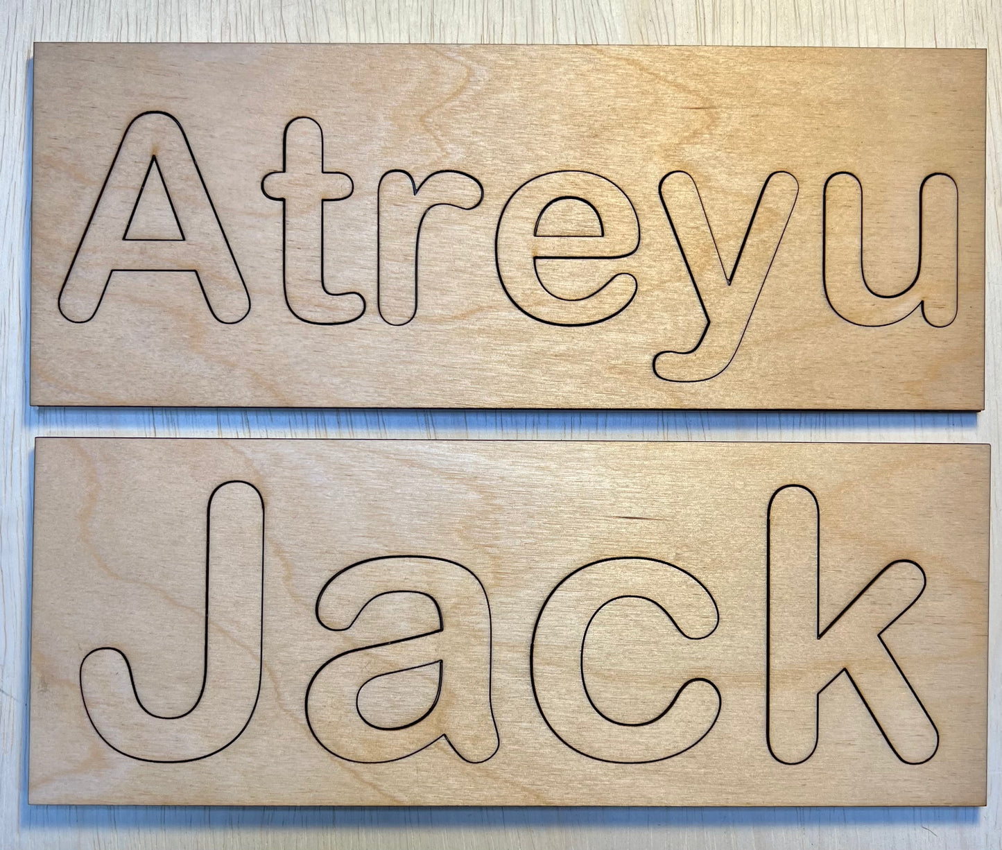Two wooden name puzzles, one spelling "Atreyu" and the other "Jack".