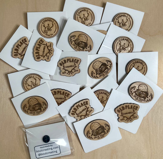 A collection of custom wooden pins featuring various designs on white backing cards.