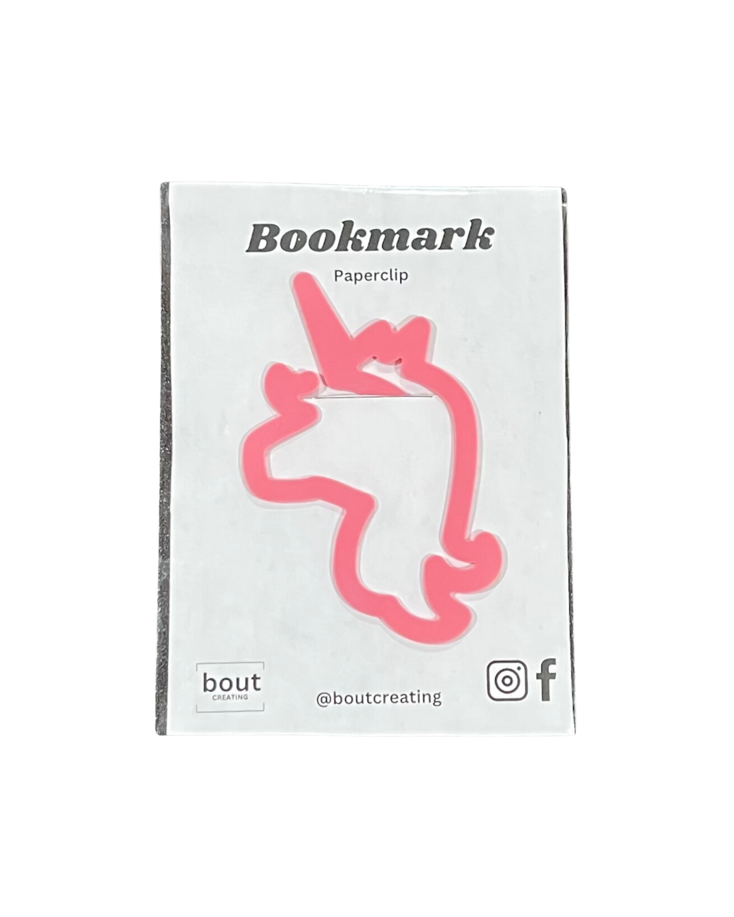 A pink unicorn-shaped paperclip bookmark is displayed on a white card.